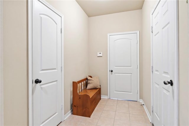 doorway with light tile patterned flooring and baseboards