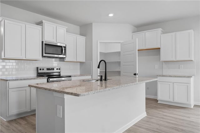 5337 Bypass Breeze Dr, Slidell, LA 70461 - kitchen with stainless steel appliances, light stone counters, light wood-type flooring, decorative backsplash, and a center island with sink