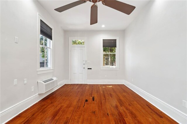 empty room with a ceiling fan, wood finished floors, a wall mounted AC, baseboards, and recessed lighting