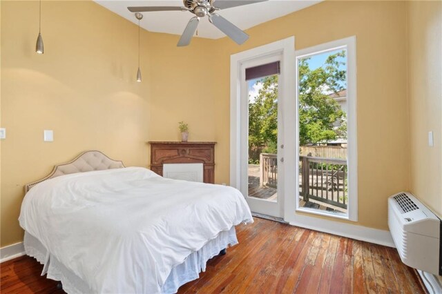 bedroom with access to exterior, hardwood / wood-style flooring, baseboards, a wall mounted AC, and a ceiling fan