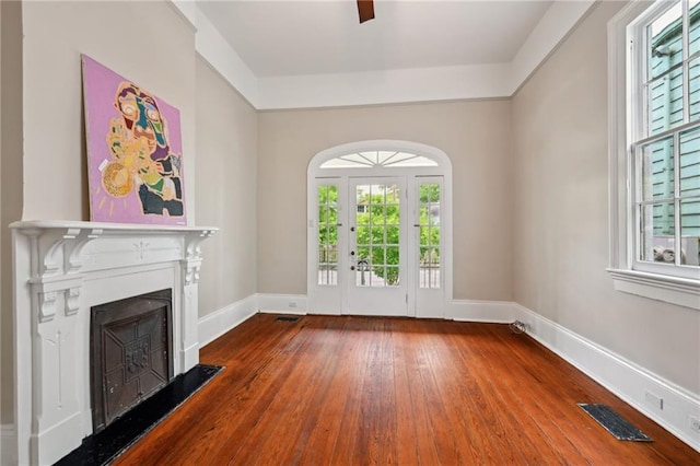 unfurnished living room featuring healthy amount of natural light, hardwood / wood-style floors, a fireplace, and baseboards
