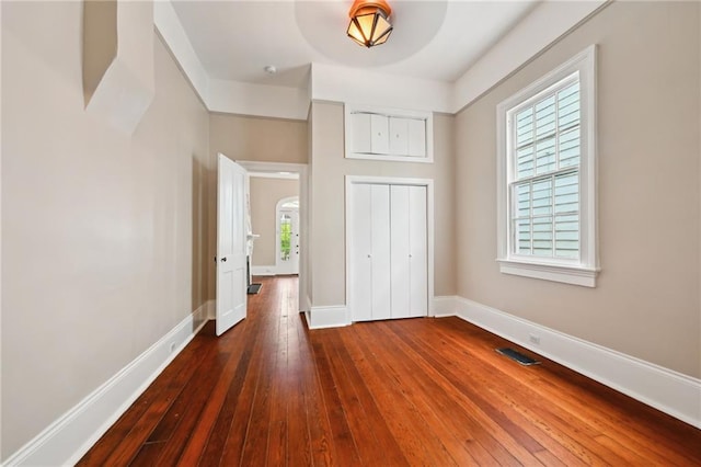 unfurnished bedroom featuring dark wood-style floors, baseboards, and a closet