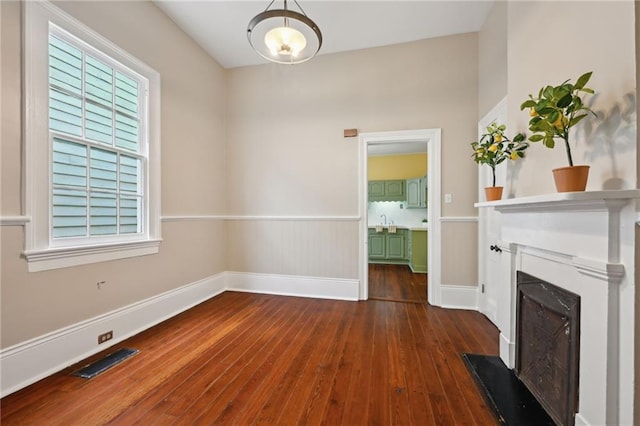 unfurnished living room featuring dark wood finished floors, a fireplace, baseboards, and a sink
