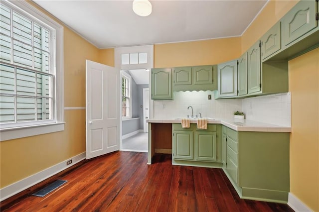 kitchen featuring green cabinets, tile countertops, dark wood-type flooring, and a sink