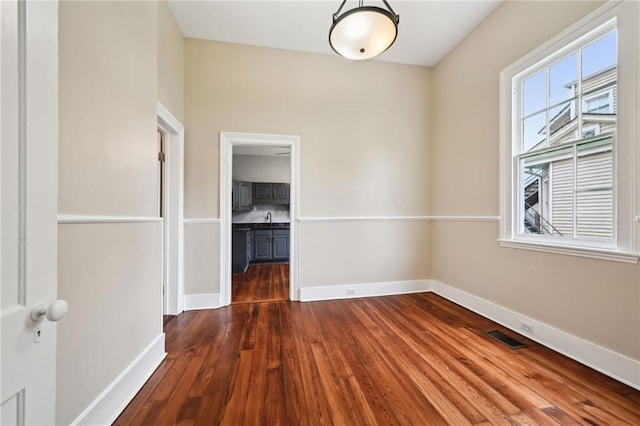 spare room featuring baseboards and dark wood finished floors