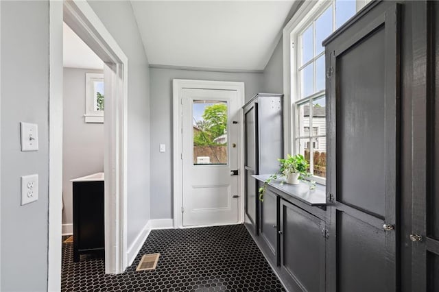 doorway with vaulted ceiling, plenty of natural light, baseboards, and dark tile patterned floors