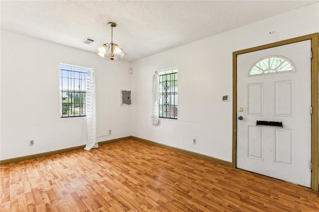930 Andry St, New Orleans, LA 70117 - foyer with light wood-type flooring, a chandelier, baseboards, electric panel, and a textured ceiling