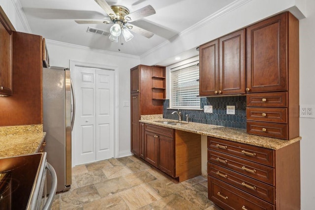 kitchen with a sink, freestanding refrigerator, ceiling fan, light stone finish flooring, and light stone counters