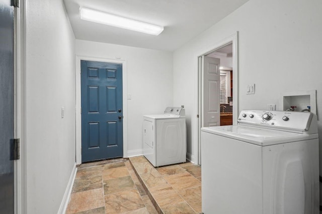 laundry room featuring separate washer and dryer, stone tile floors, and baseboards