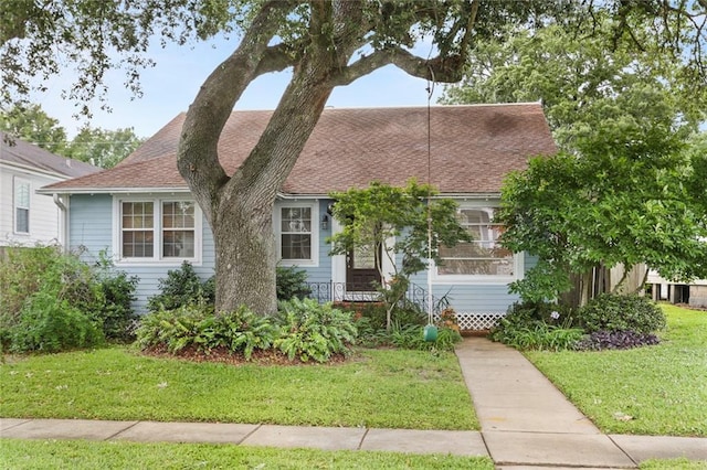 view of front of house with a front yard and roof with shingles