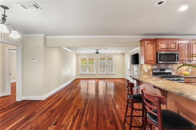 kitchen featuring stainless steel appliances, baseboards, dark wood finished floors, brown cabinetry, and crown molding