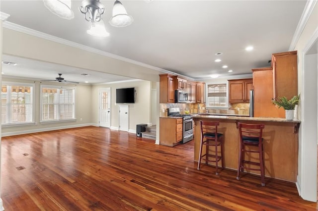 kitchen featuring appliances with stainless steel finishes, brown cabinets, dark wood finished floors, tasteful backsplash, and crown molding