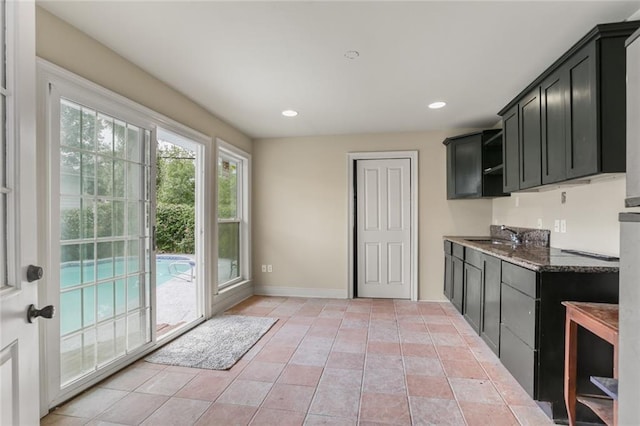 kitchen featuring dark cabinets, a sink, baseboards, and recessed lighting