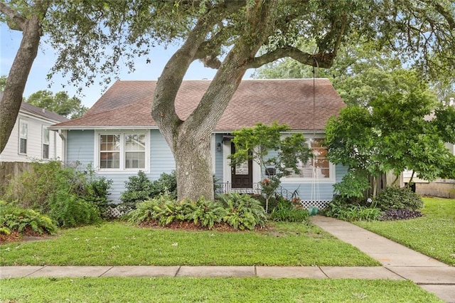 view of front of property featuring a front yard and a shingled roof