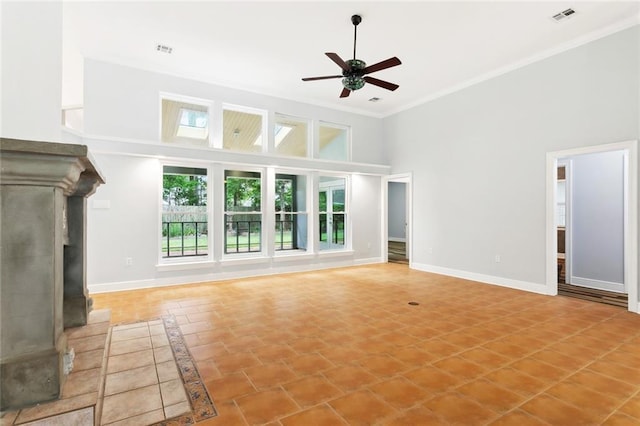 1306 Woodmere Dr, Mandeville, LA 70471 - unfurnished living room featuring a towering ceiling, ceiling fan, ornamental molding, a fireplace with raised hearth, and baseboards