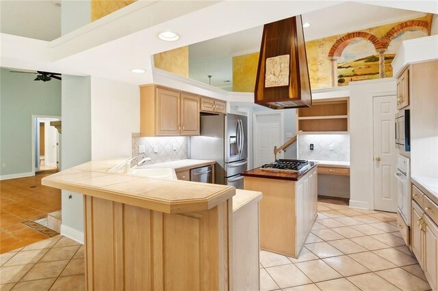 1306 Woodmere Dr, Mandeville, LA 70471 - kitchen featuring light tile patterned flooring, a sink, appliances with stainless steel finishes, a center island, and a peninsula