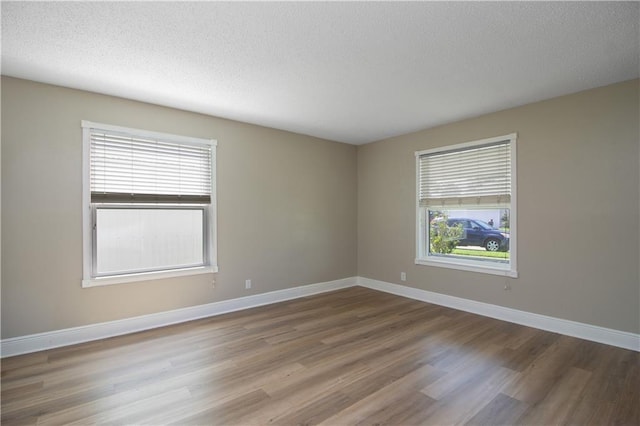 spare room with wood finished floors, baseboards, and a textured ceiling