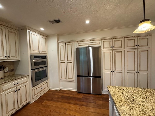208 Noble Dr, Brookhaven, MS 39601 - kitchen with appliances with stainless steel finishes, cream cabinets, dark wood-style flooring, a textured ceiling, and light stone countertops