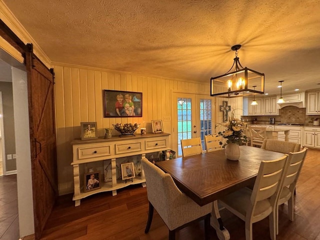 208 Noble Dr, Brookhaven, MS 39601 - dining space featuring a barn door, a chandelier, dark wood-style floors, a textured ceiling, and french doors