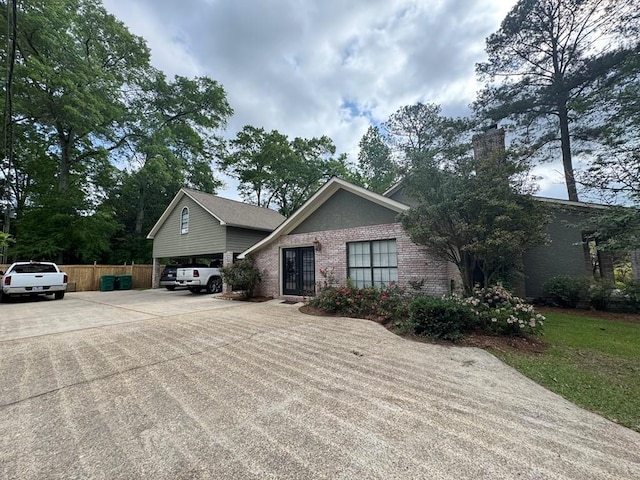 208 Noble Dr, Brookhaven, MS 39601 - view of front facade featuring fence, brick siding, concrete driveway, a chimney, and a carport