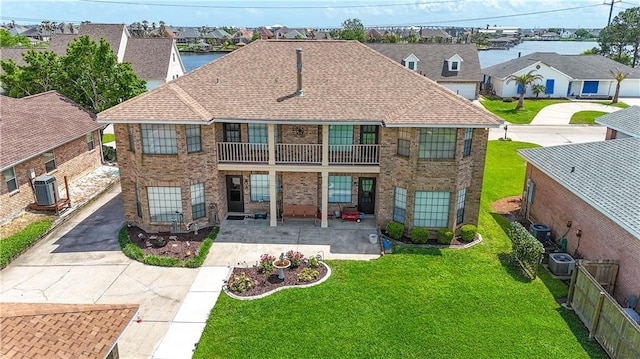 back of house with brick siding, a residential view, and a balcony