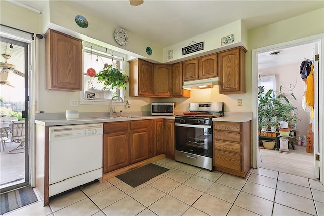 kitchen featuring stainless steel appliances, a sink, under cabinet range hood, and light countertops