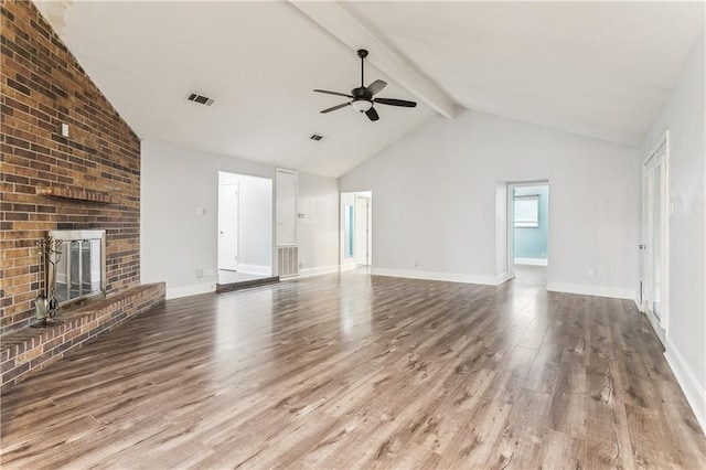 unfurnished living room with wood finished floors, a ceiling fan, beam ceiling, a fireplace, and baseboards