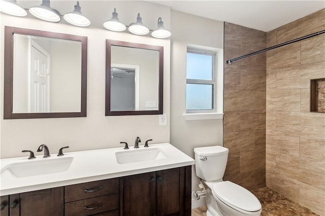 full bathroom featuring toilet, double vanity, and tiled shower