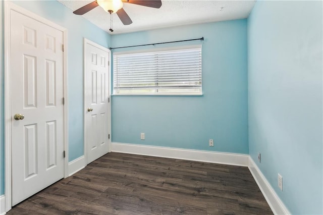unfurnished bedroom with dark wood-style floors, baseboards, and a ceiling fan