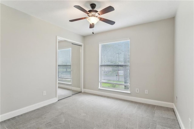 unfurnished bedroom featuring carpet flooring, baseboards, a closet, and a ceiling fan