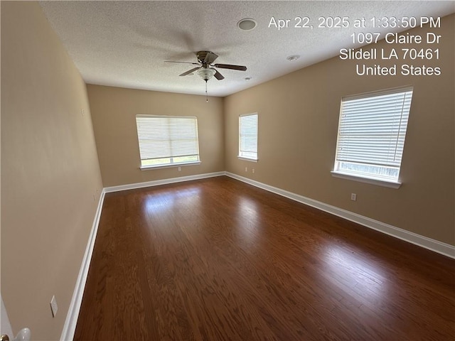 empty room featuring a textured ceiling, dark wood-style flooring, ceiling fan, and baseboards