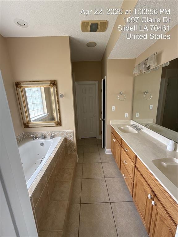 bathroom featuring tile patterned floors, a textured ceiling, a jetted tub, and double vanity