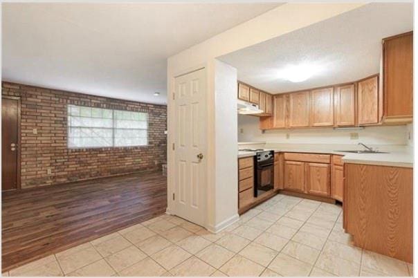 2305 Cleary Ave Unit 106, Metairie, LA 70001 - kitchen with stove, brick wall, under cabinet range hood, light countertops, and a sink