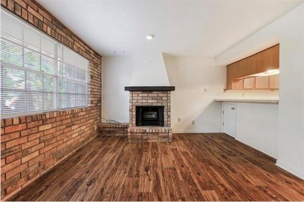 2305 Cleary Ave Unit 106, Metairie, LA 70001 - unfurnished living room featuring healthy amount of natural light, wood finished floors, a fireplace, and brick wall
