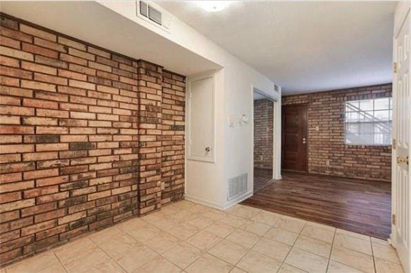 2305 Cleary Ave Unit 106, Metairie, LA 70001 - unfurnished room featuring brick wall, baseboards, and light wood-type flooring