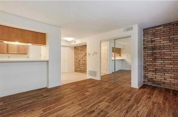 2305 Cleary Ave Unit 106, Metairie, LA 70001 - unfurnished living room featuring brick wall and wood finished floors