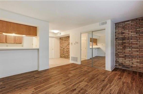 2305 Cleary Ave Unit 106, Metairie, LA 70001 - unfurnished living room with brick wall and wood finished floors