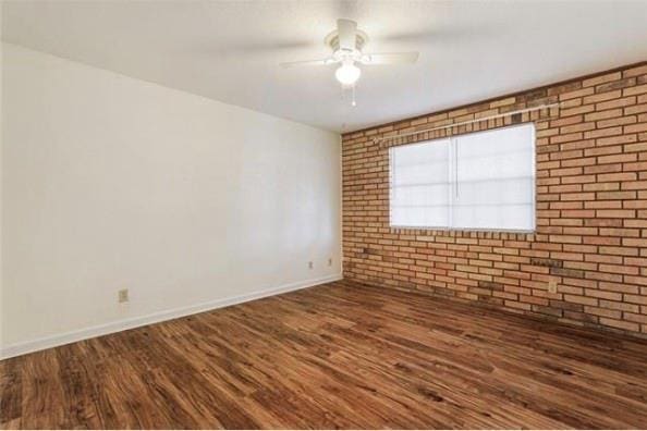 2305 Cleary Ave Unit 106, Metairie, LA 70001 - spare room featuring wood finished floors, brick wall, a ceiling fan, and baseboards