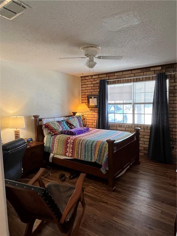 2305 Cleary Ave Unit 106, Metairie, LA 70001 - bedroom featuring a textured ceiling, dark wood finished floors, brick wall, and a ceiling fan