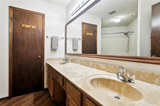 911 Forest Loop, Mandeville, LA 70471 - full bathroom with wood finished floors, double vanity, a textured ceiling, and a shower