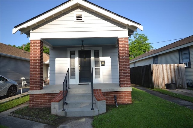 shotgun-style home with fence, a porch, and brick siding