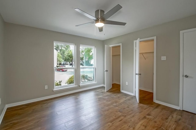 147 W Chamale Cv Unit 147, Slidell, LA 70460 - unfurnished bedroom with wood finished floors, baseboards, a walk in closet, and a ceiling fan