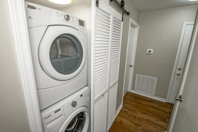 147 W Chamale Cv Unit 147, Slidell, LA 70460 - laundry room with estacked washer and dryer, dark wood finished floors, a barn door, and baseboards