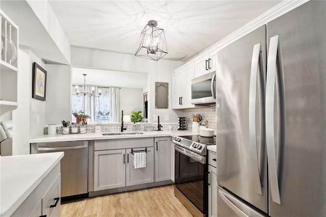 740 Heavens Dr Unit 8, Mandeville, LA 70471 - kitchen featuring appliances with stainless steel finishes, a sink, a chandelier, light wood finished floors, and light countertops