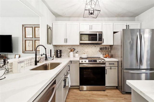 740 Heavens Dr Unit 8, Mandeville, LA 70471 - kitchen with stainless steel appliances, a sink, light wood-style flooring, backsplash, and white cabinets