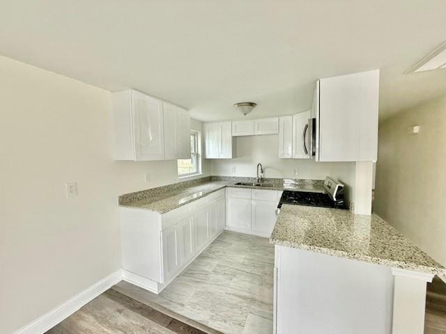 559 Resor Ave, Harahan, LA 70123 - kitchen with gas range, light stone counters, a sink, stainless steel microwave, and baseboards