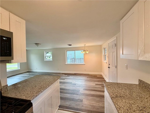 559 Resor Ave, Harahan, LA 70123 - kitchen with stainless steel microwave, dark wood-style floors, white cabinets, and light stone counters