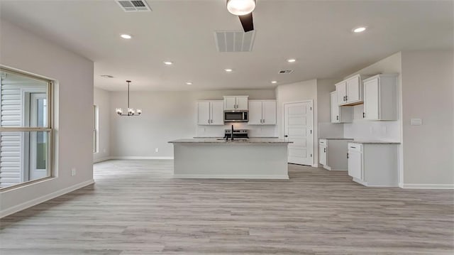 kitchen with appliances with stainless steel finishes, light wood-type flooring, white cabinets, baseboards, and recessed lighting