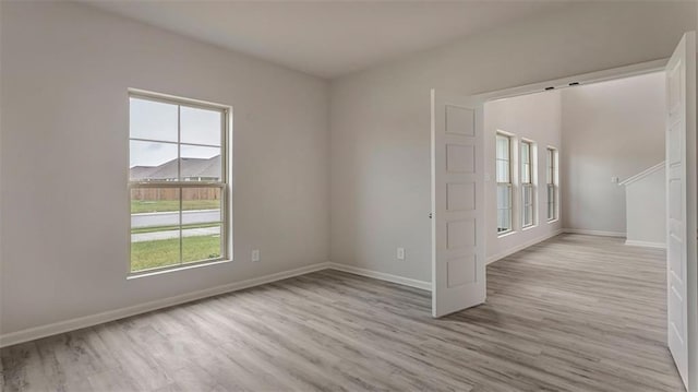 empty room featuring wood finished floors, plenty of natural light, and baseboards