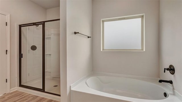 full bath with a stall shower, a garden tub, and wood finished floors